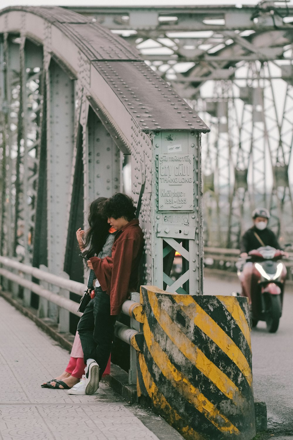 a couple of people that are sitting on a bridge