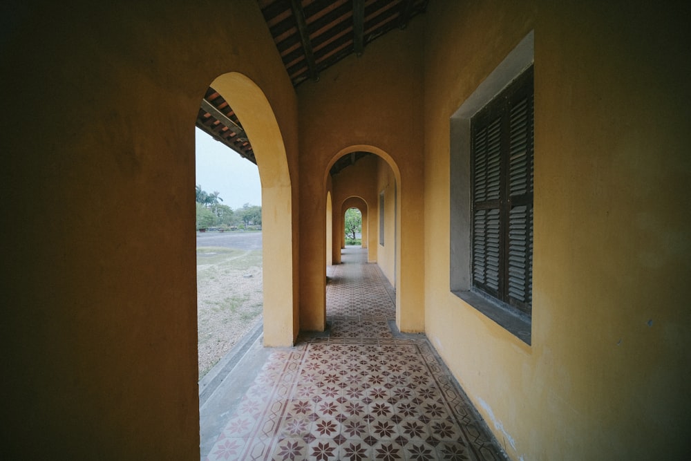 um longo corredor com piso frio e janelas arqueadas