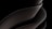 A sleek, smooth, and abstract form consisting of overlapping curved surfaces, primarily in dark tones and gradients. The design is fluid and modern, suggesting movement and elegance.