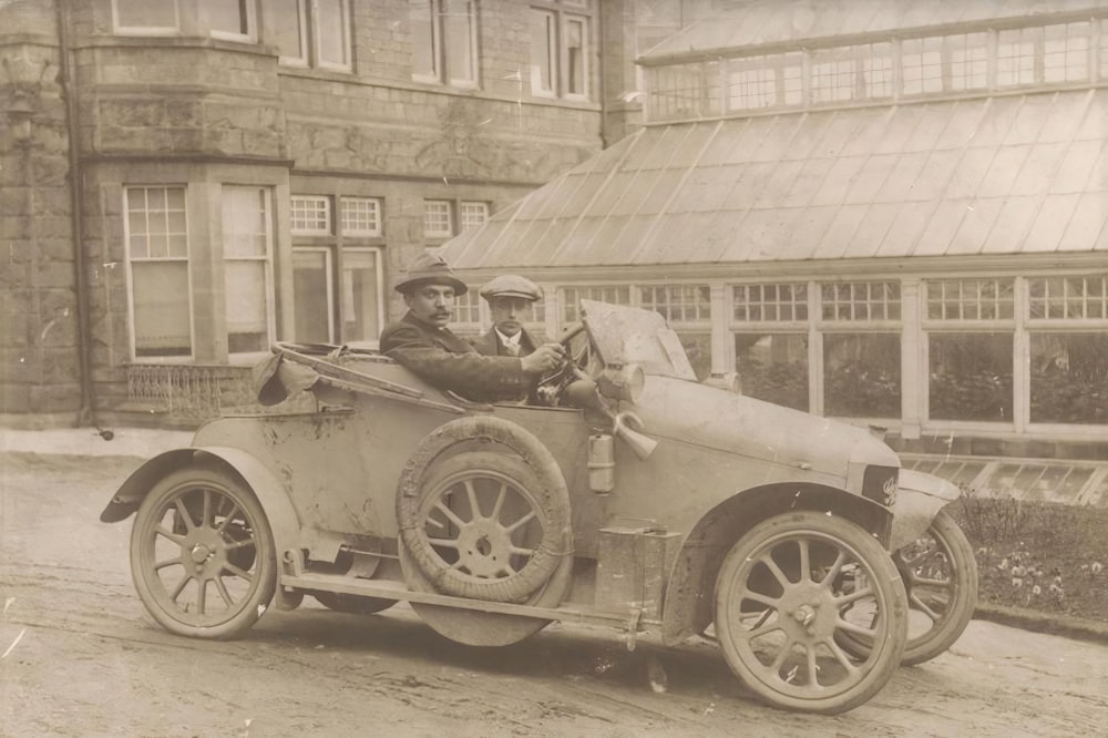 an old photo of two men in an old car