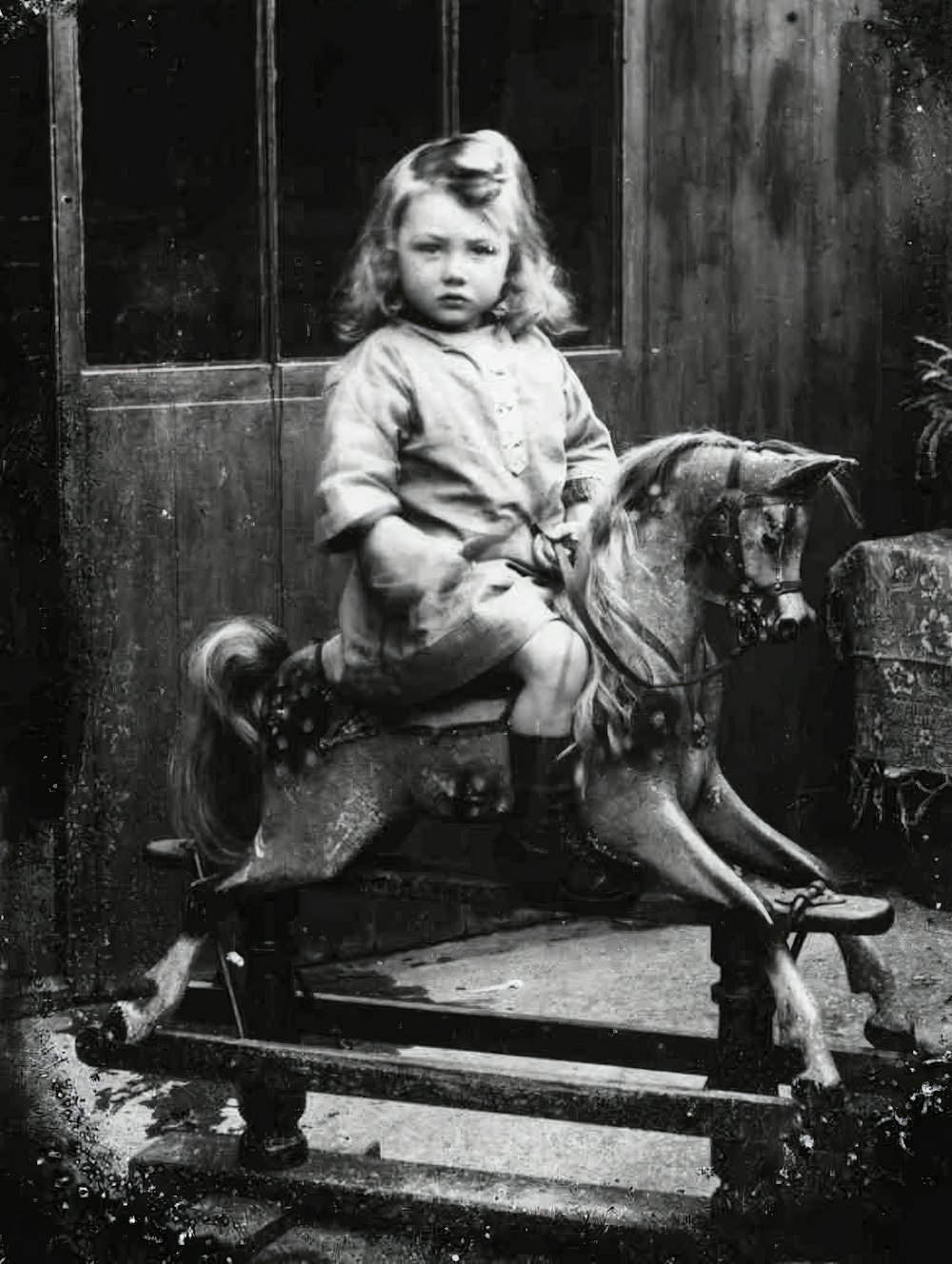 a little girl sitting on top of a wooden horse
