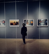 An artist thoughtfully arranging photographs on a gallery display board.