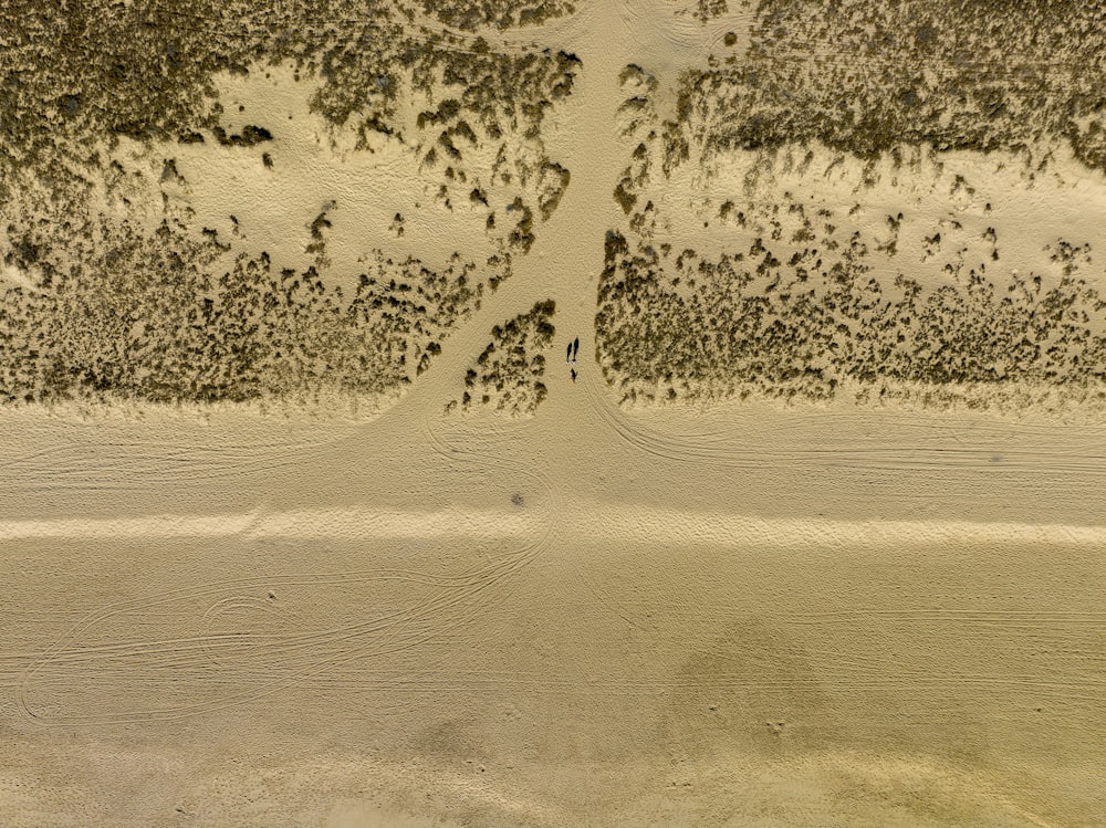 an aerial view of a sandy beach with footprints in the sand