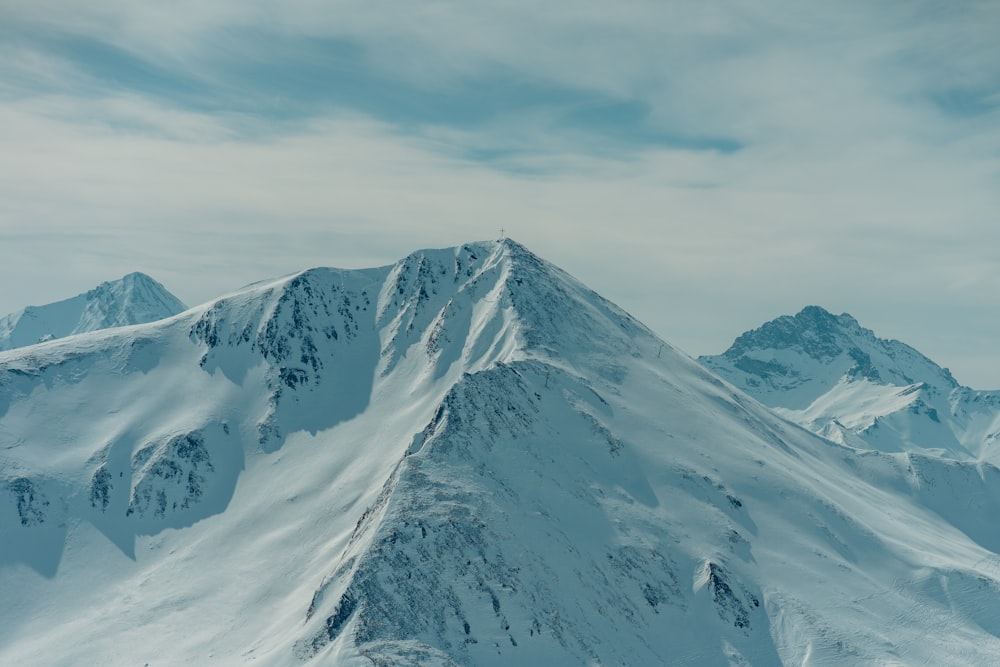 a mountain covered in snow under a cloudy sky