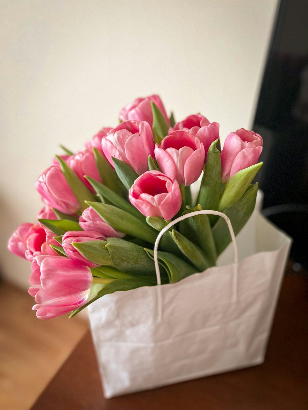 a bouquet of pink tulips in a white paper bag