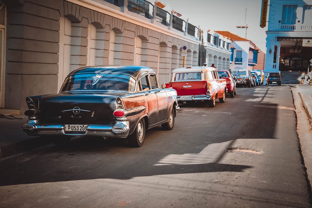 a row of old cars parked on the side of a road