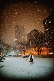 a person walking in the snow in a city at night