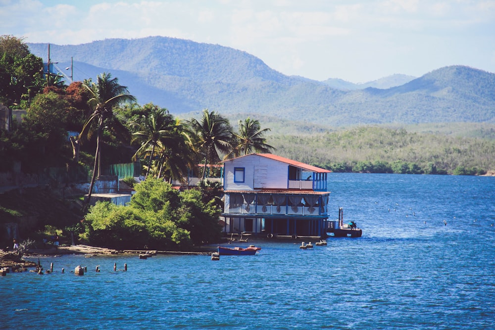 a house on the water with mountains in the background