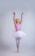 A joyful young girl in a pink ballet outfit practicing at the barre.