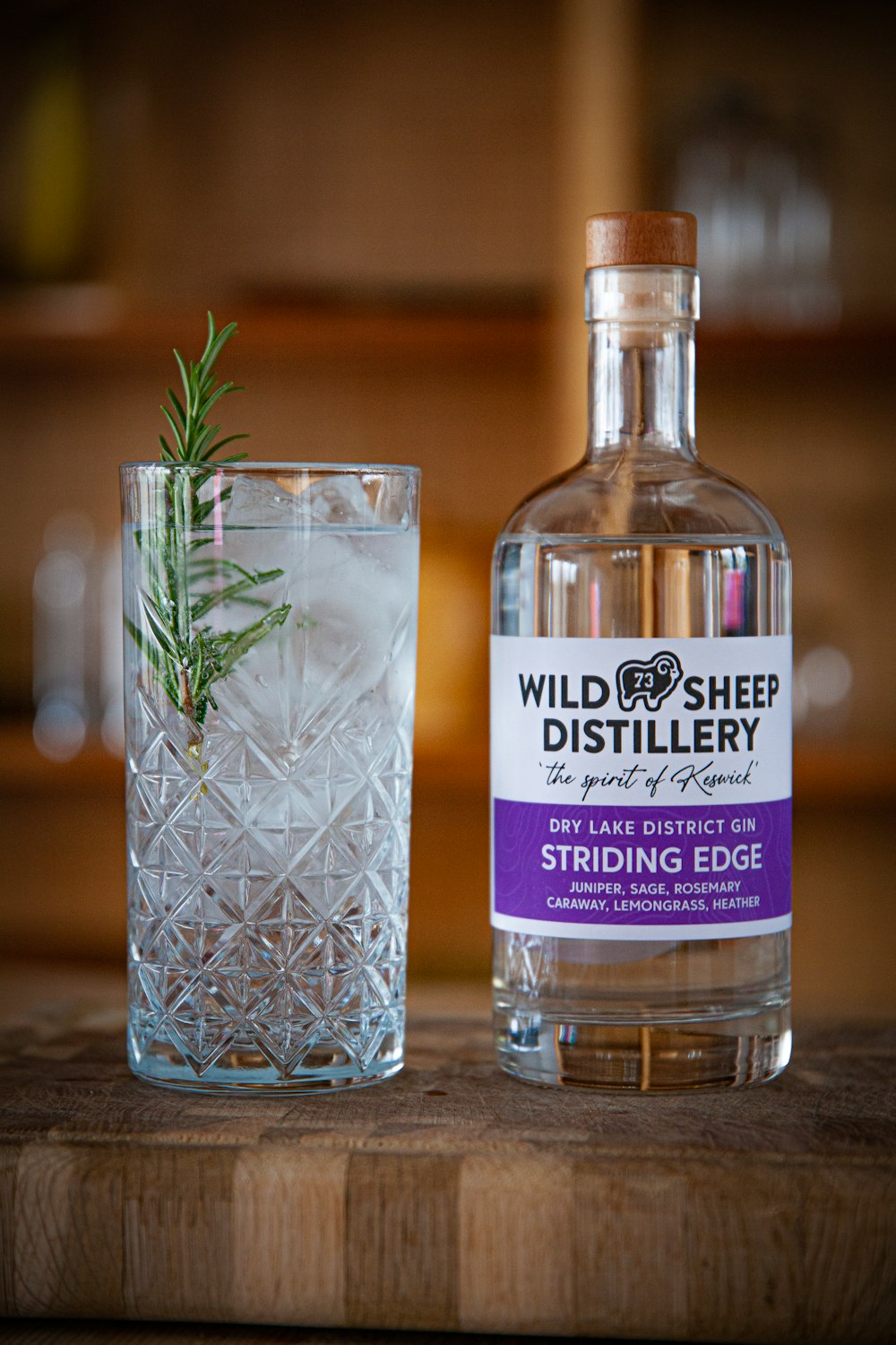 a bottle of wild sheep distillery next to a glass with a rosemary