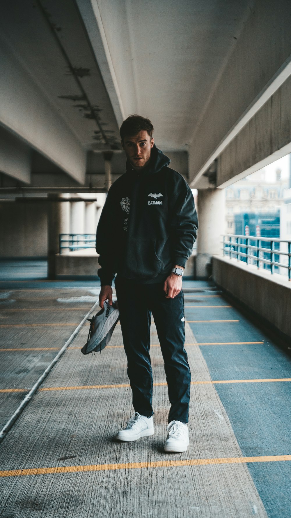 a man standing in a parking garage holding a tennis racquet