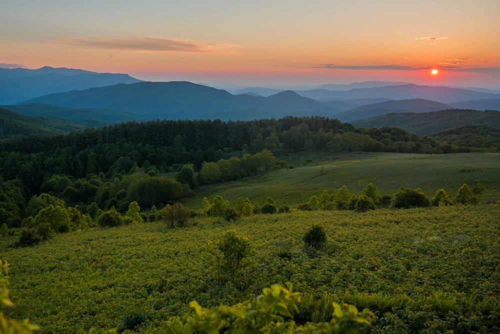 the sun is setting over the mountains in the distance