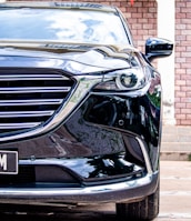 Close-up of a shiny car grill reflecting the minimalist black backdrop.