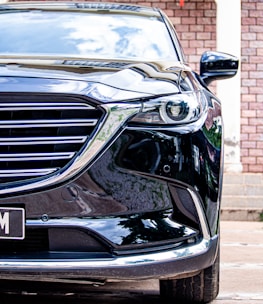Close-up of a shiny car grill reflecting the minimalist black backdrop.