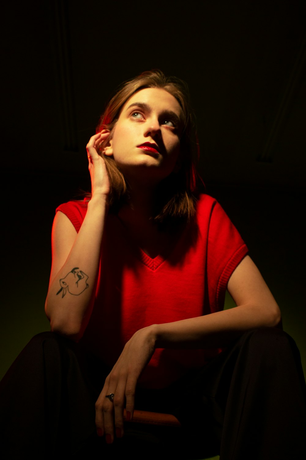 a woman in a red shirt sitting in the dark