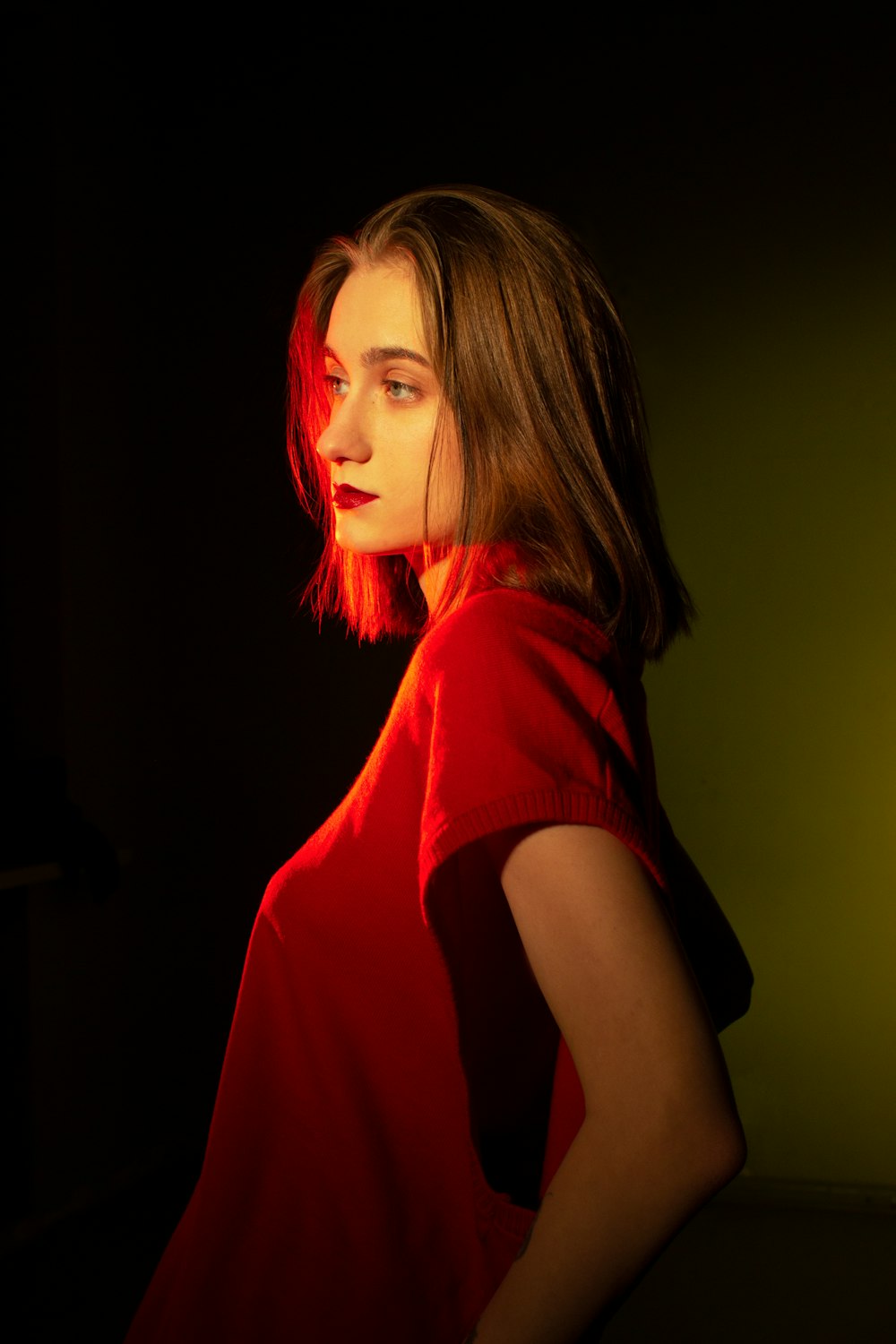 a woman in a red shirt standing in a dark room