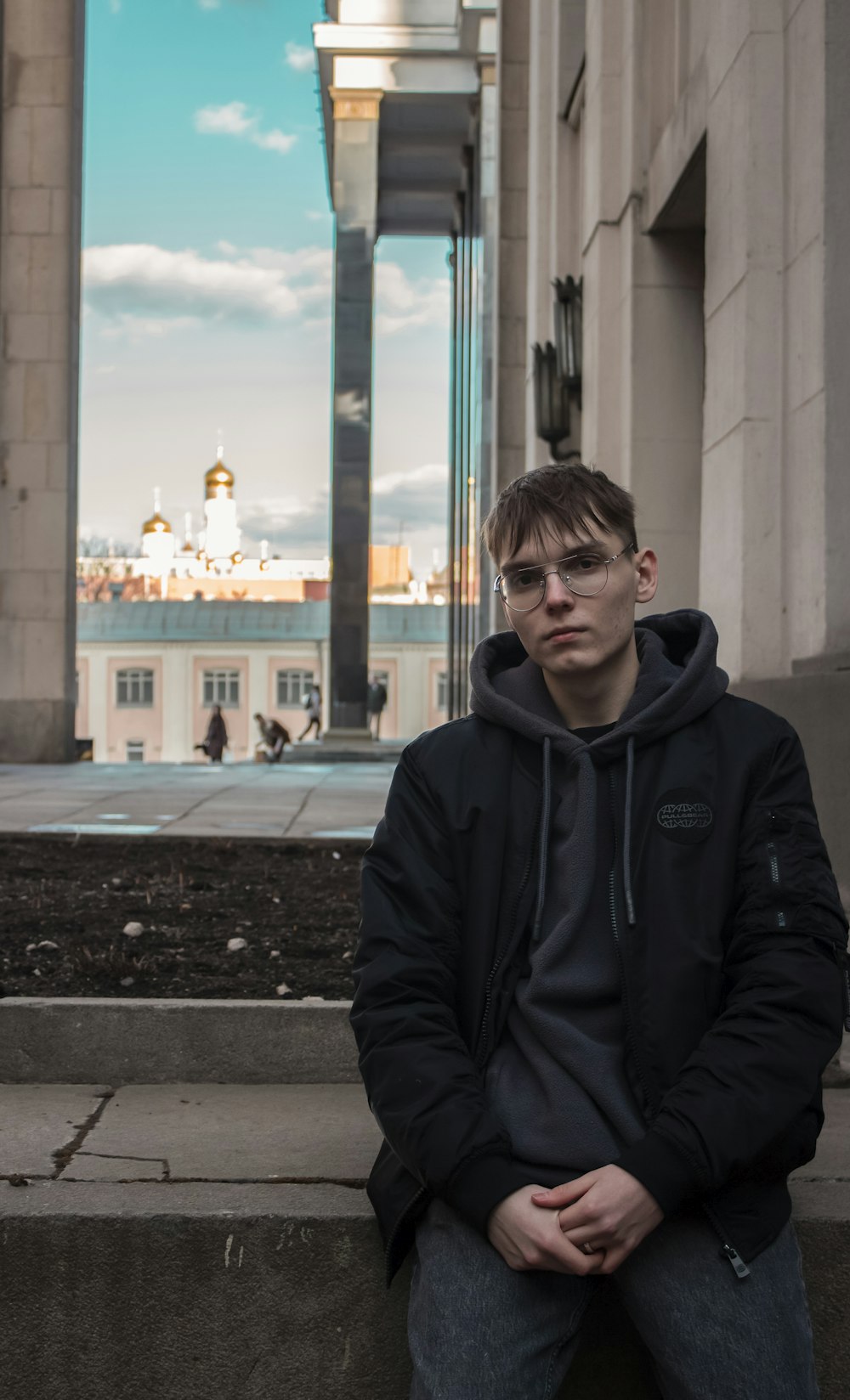 a man sitting on a ledge in front of a building