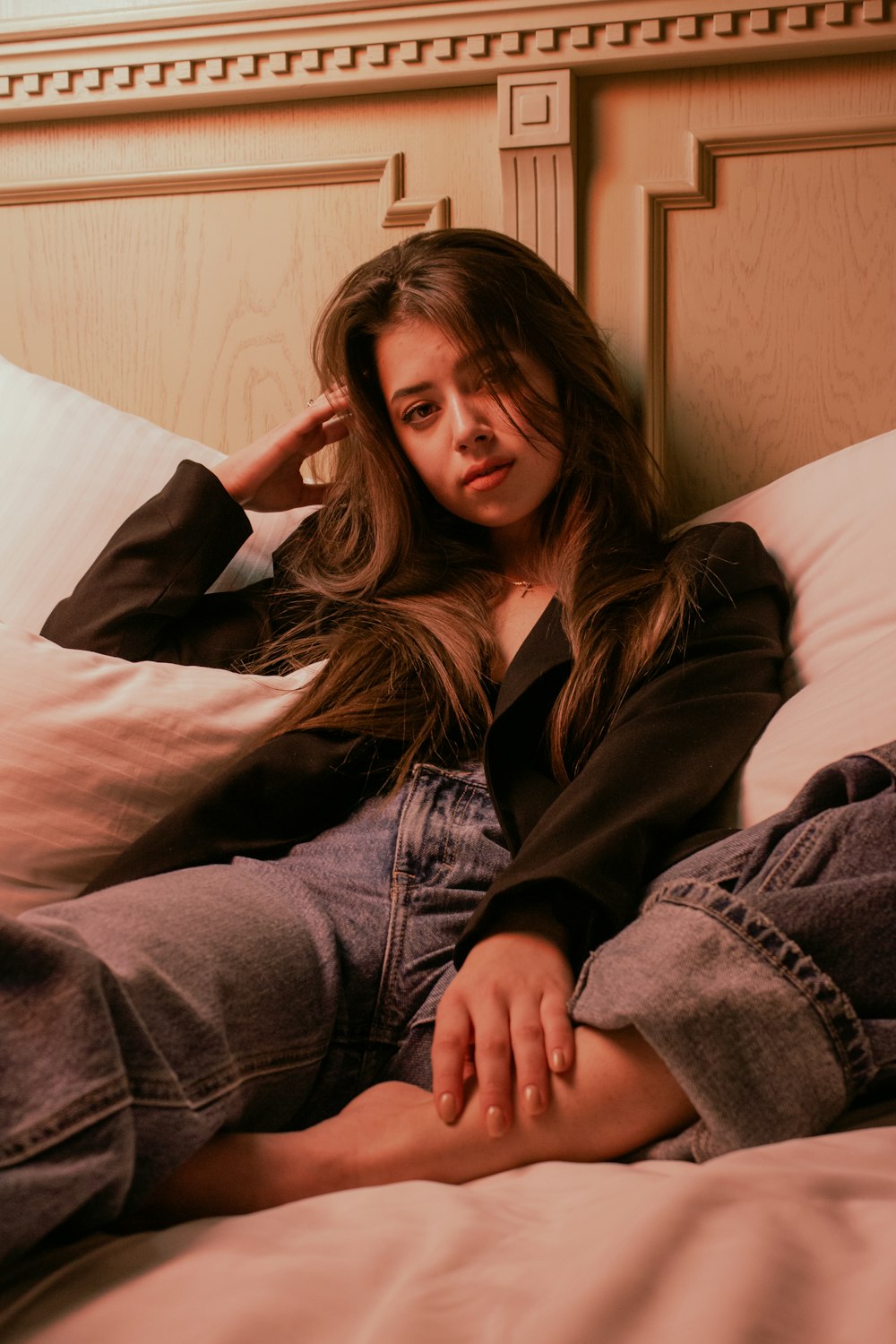 a woman laying on top of a bed next to pillows