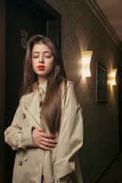 a woman in a trench coat standing in a hallway