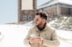 a man standing in the snow looking at his cell phone