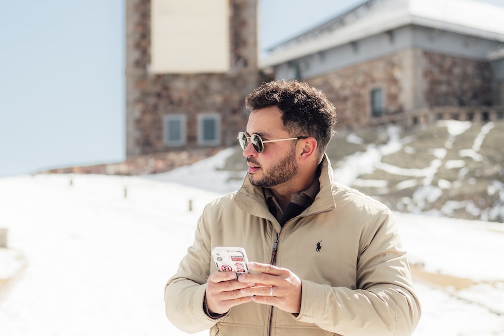 a man standing in the snow looking at his cell phone