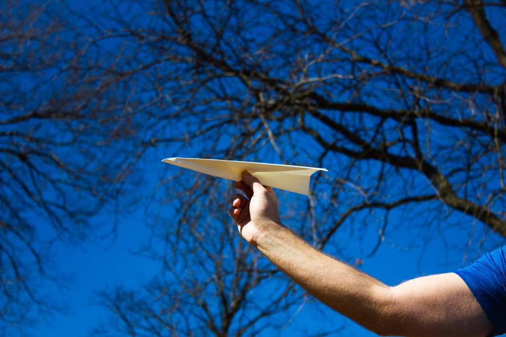 um homem segurando um avião de papel em sua mão