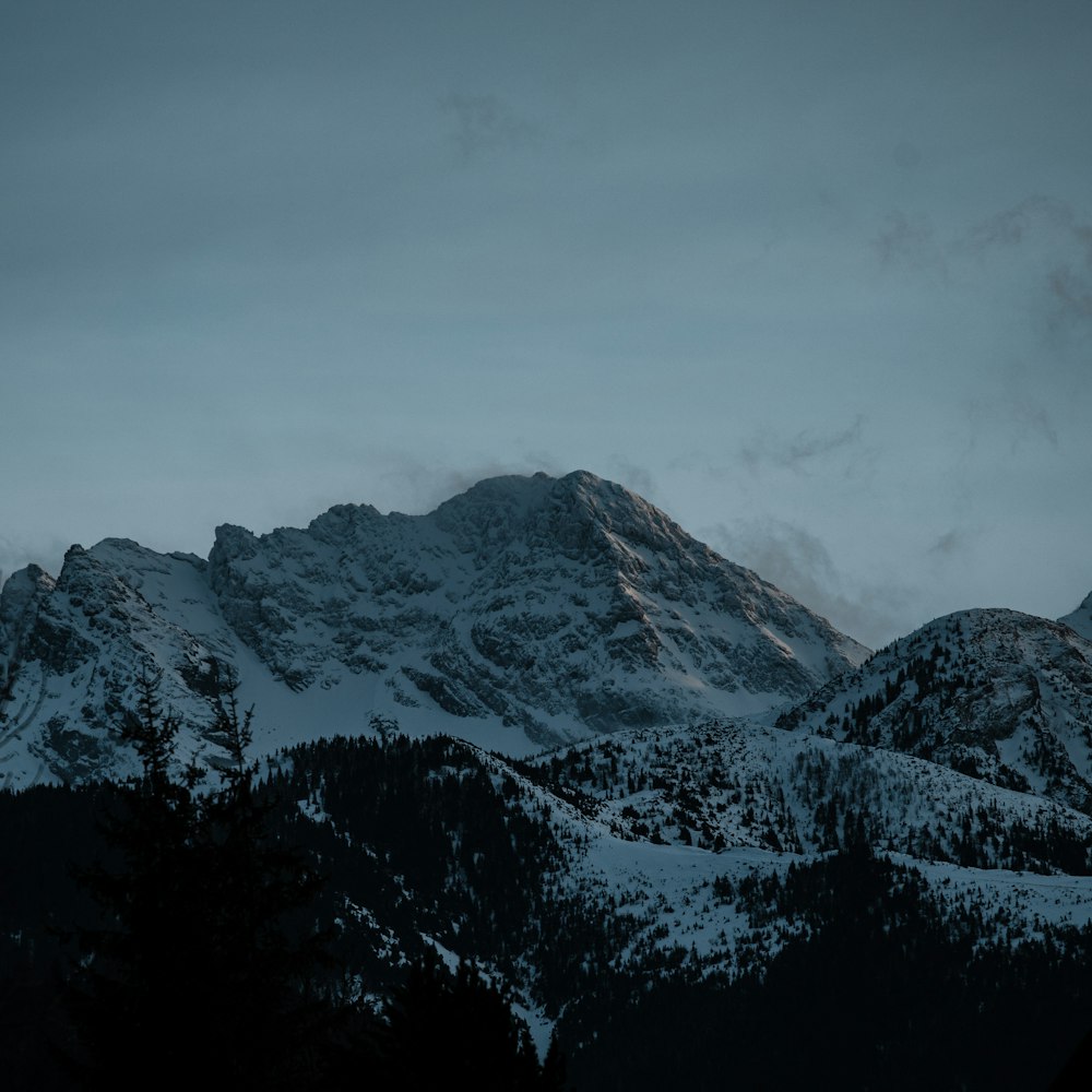 a snowy mountain range with a few clouds in the sky