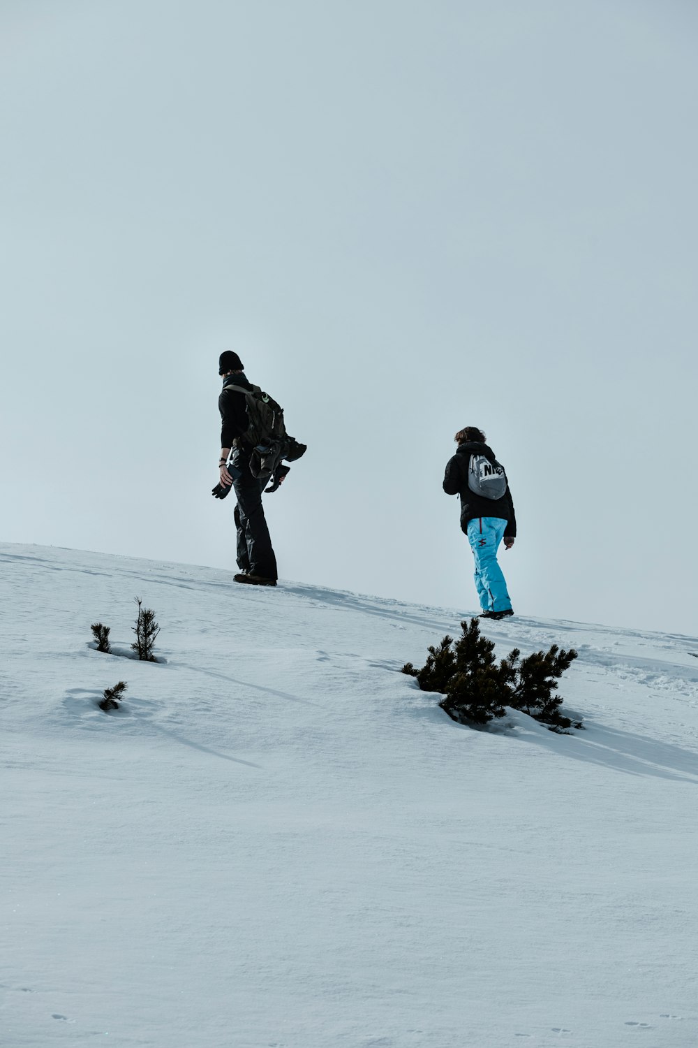 two snowboarders are standing on a snowy hill