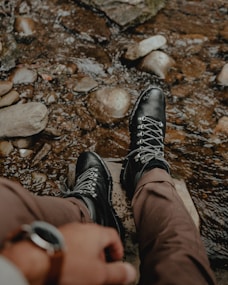 a person wearing black shoes standing in a stream