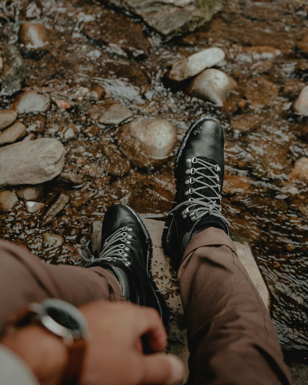 a person wearing black shoes standing in a stream