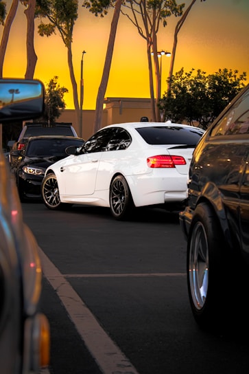 A sleek white Toyota Hiace parked at a busy airport drop-off zone during sunset.