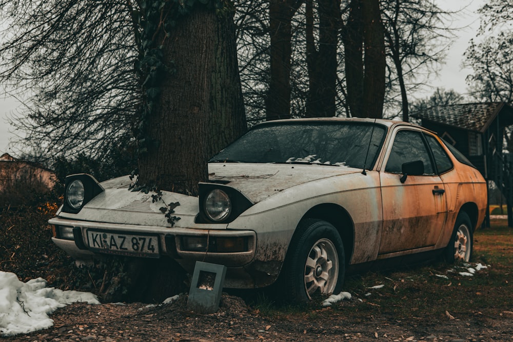 a rusted out car is parked in the woods