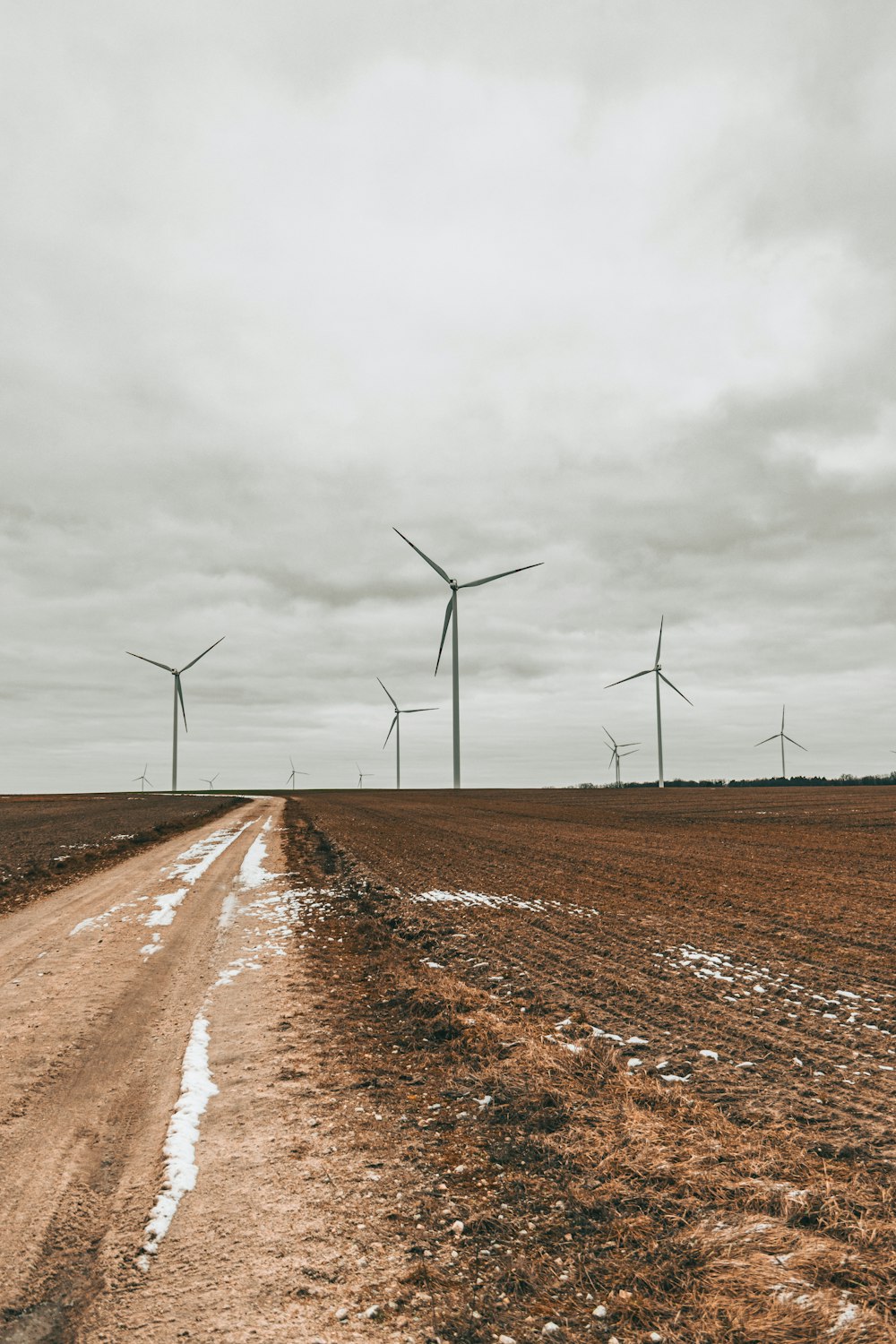 a dirt road in front of wind turbines