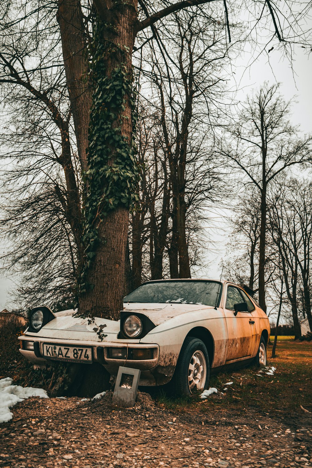 an old car is parked next to a tree