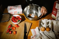 A wooden table topped with a bowl of strawberries and eggs
