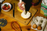 A smiling student carefully decorating a colorful cake in a bright kitchen