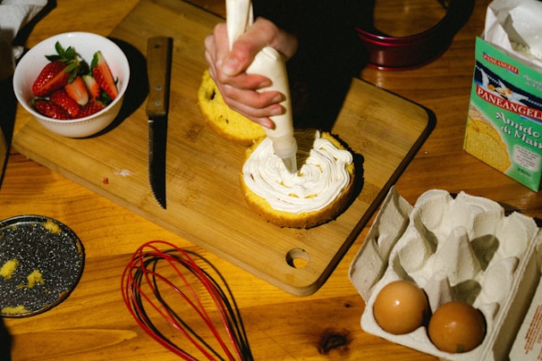 A chef decorating a cake with smooth frosting in a kitchen.