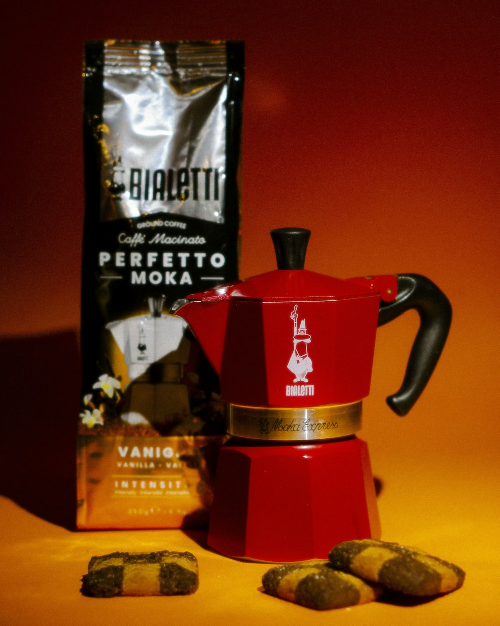 a red coffee pot sitting next to a bag of coffee