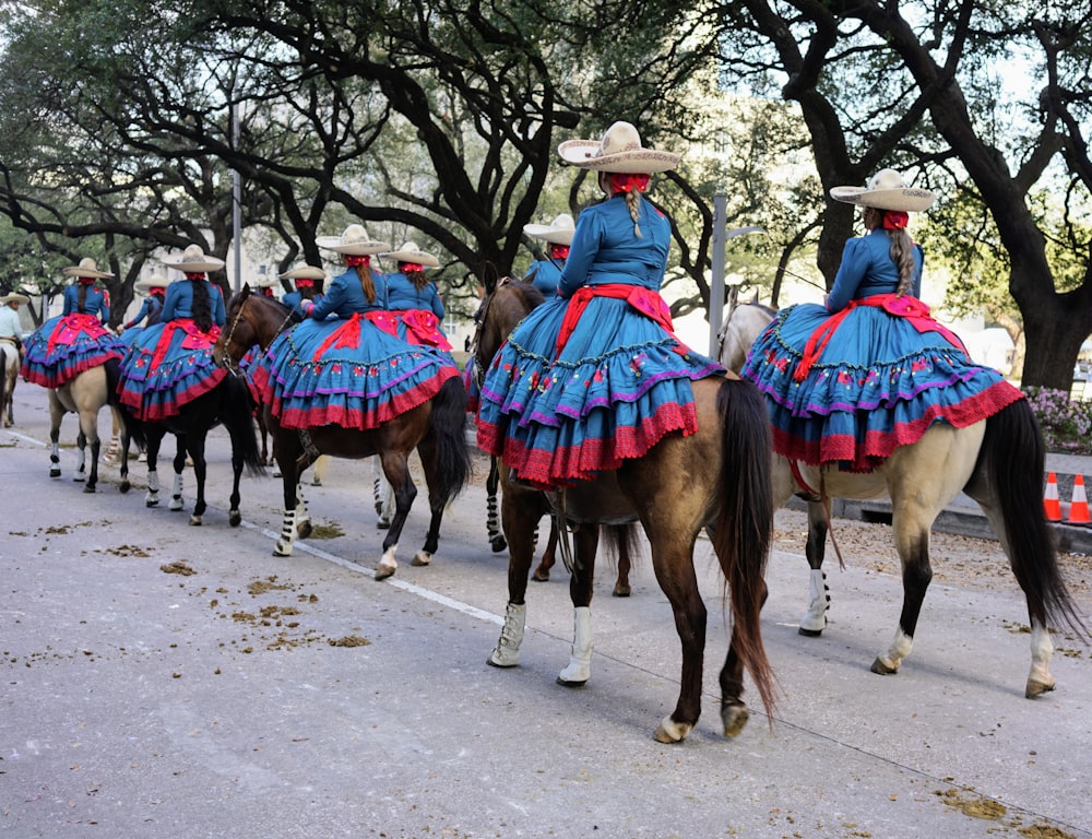 a group of people riding horses down a street