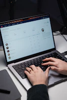 Close-up of hands typing on a laptop with customer service dashboard on screen