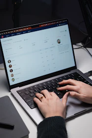 A creator smiling while quickly typing on a laptop with video ideas appearing on screen.