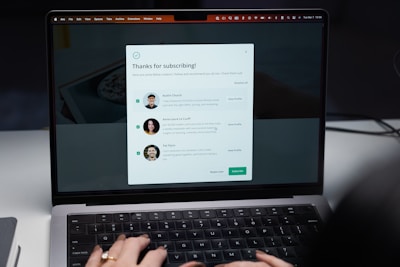 A laptop screen displaying a subscription confirmation message. The message includes a title saying 'Thanks for subscribing!' and introduces profiles of three individuals with their photographs and brief descriptions. The user's hands are visible typing on the laptop keyboard.