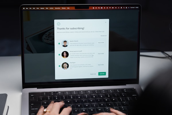 A laptop screen displaying a subscription confirmation message. The message includes a title saying 'Thanks for subscribing!' and introduces profiles of three individuals with their photographs and brief descriptions. The user's hands are visible typing on the laptop keyboard.