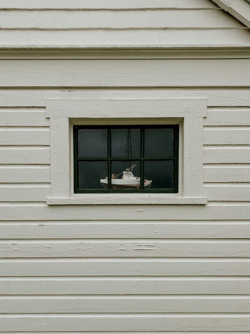 a boat is seen through a window of a white house