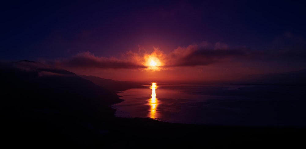 a sunset over a body of water with clouds in the sky