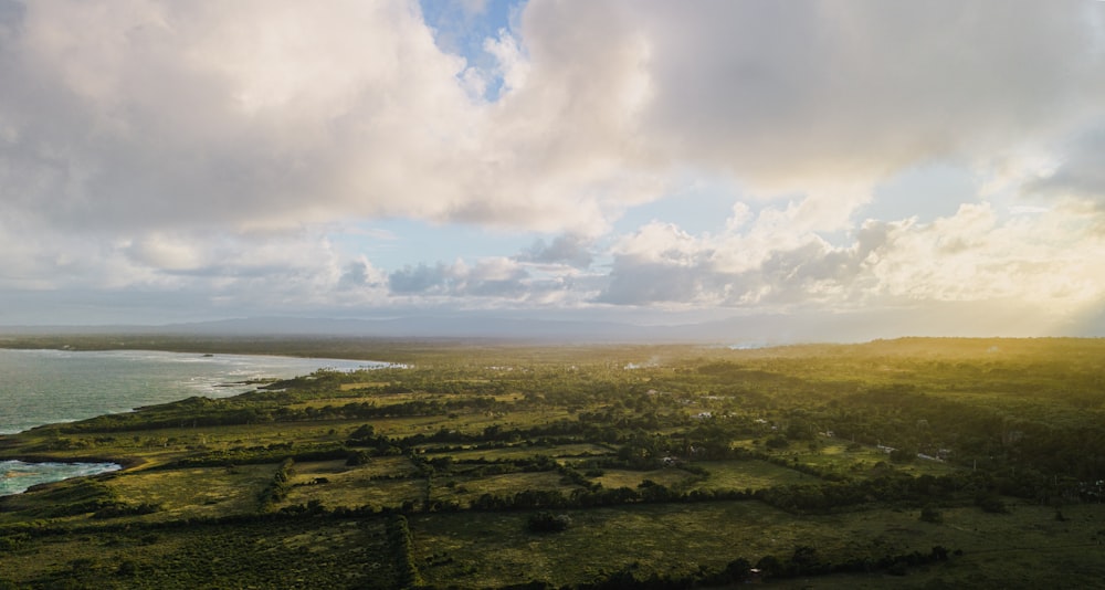 an aerial view of a lush green field next to a body of water