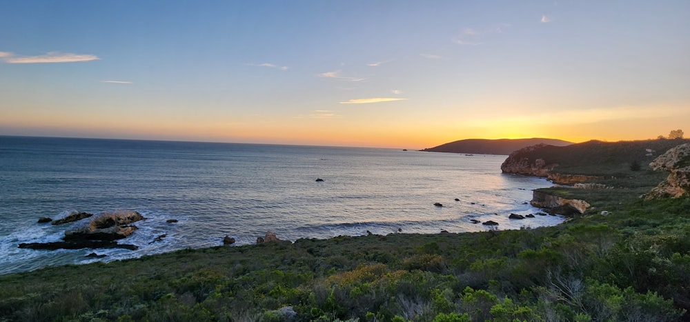 the sun is setting over the ocean on the coast