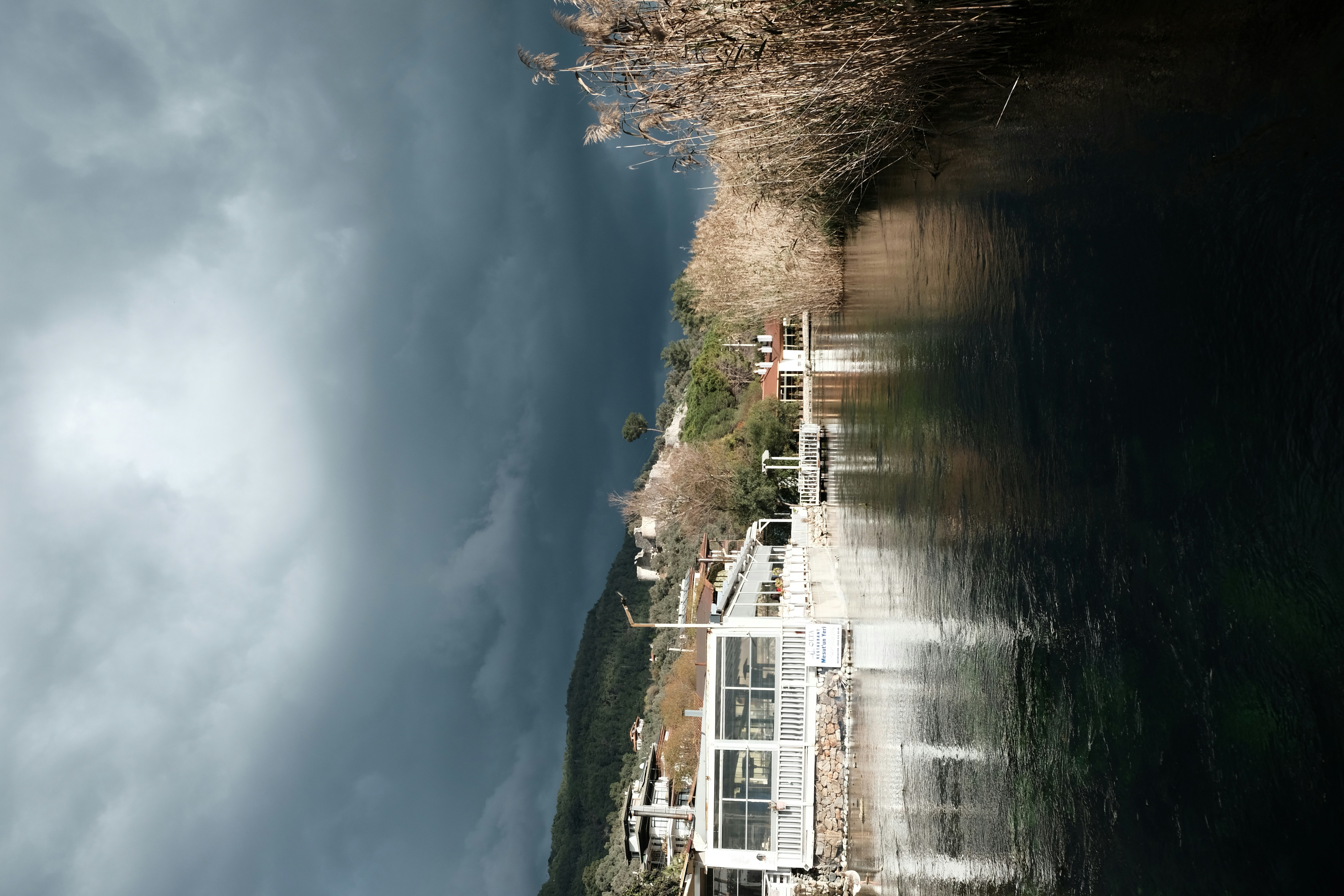 Una casa sentada al lado de un río bajo un cielo nublado