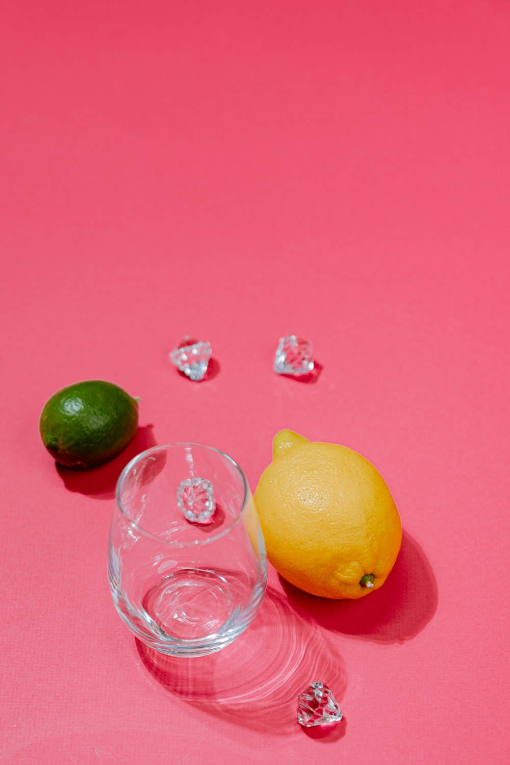 a lemon and a glass of water on a pink surface