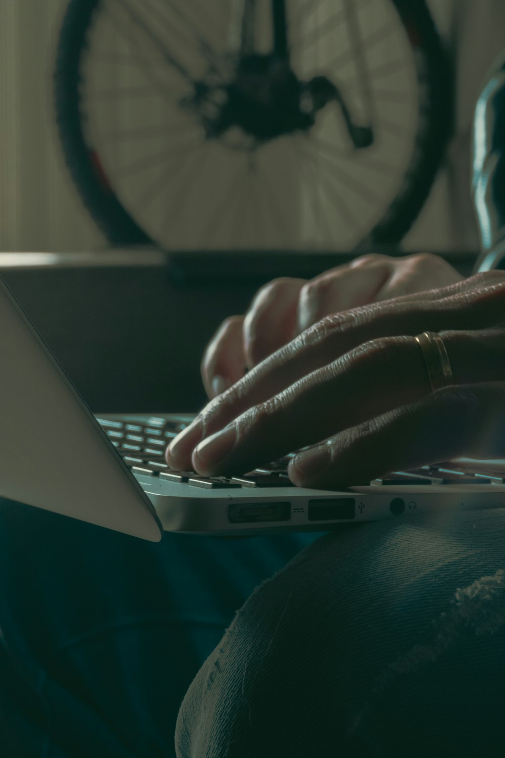 a person typing on a laptop with a bike in the background